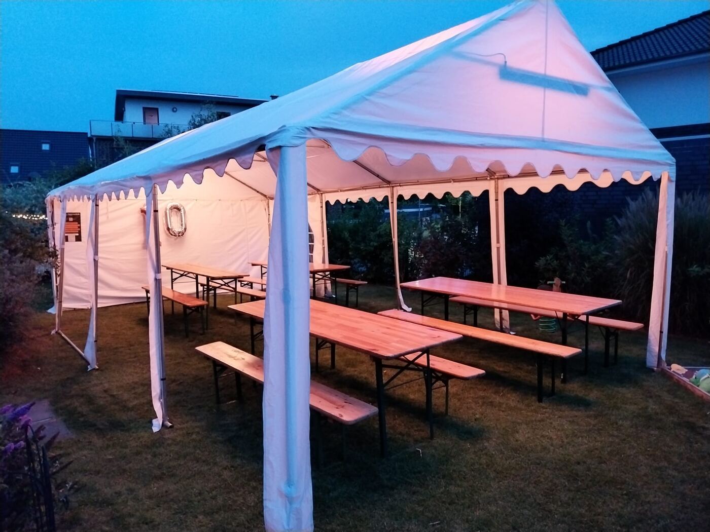 Partyzelt mit Bierzeltgarnituren in der Abenddämmerung